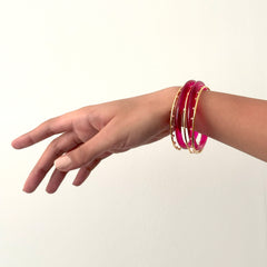Hand wearing pink and gold bangles on a white background